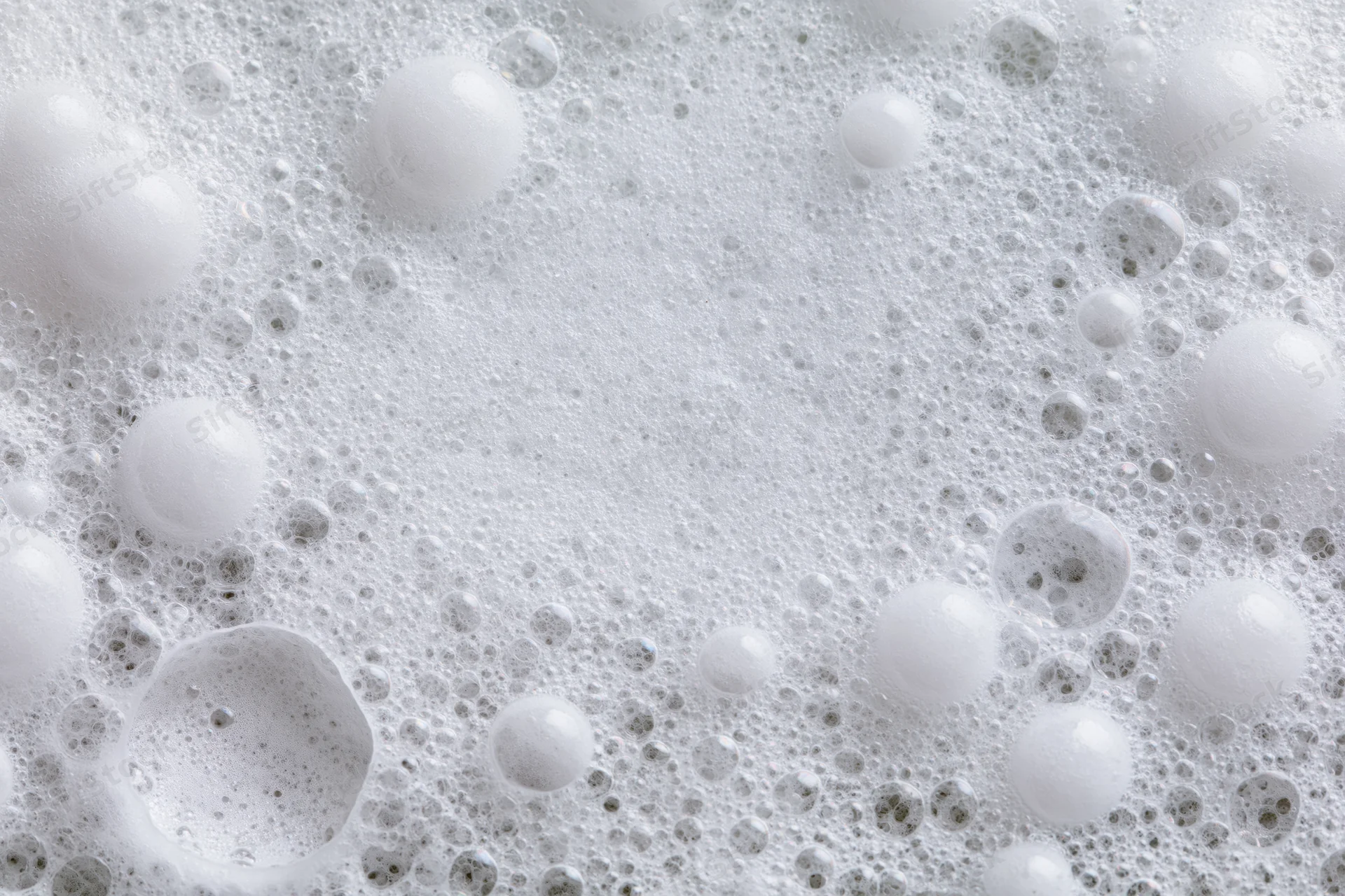 Closeup of white soap foam and bubbles scattered across a wet surface