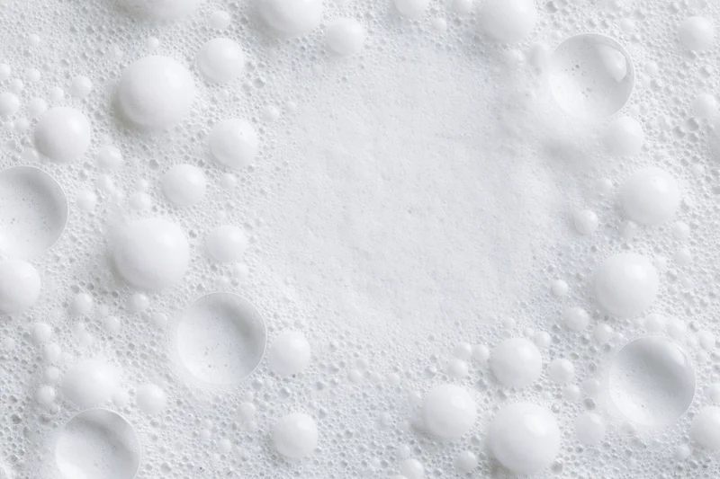 White soap foam with scattered bubbles forming a textured surface