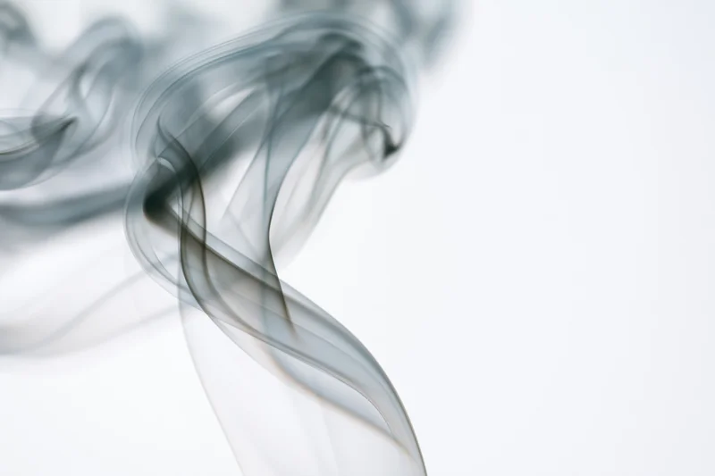 Wispy smoke curling and rising against a pure white background