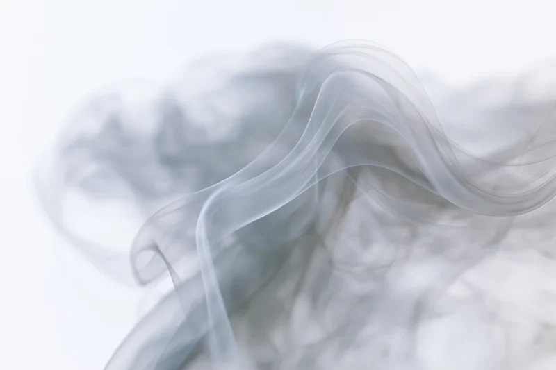 Wispy smoke curling and rising against a pure white background