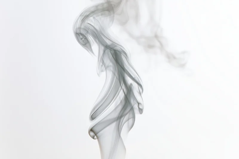 Wispy smoke plume rising and curling against a white background