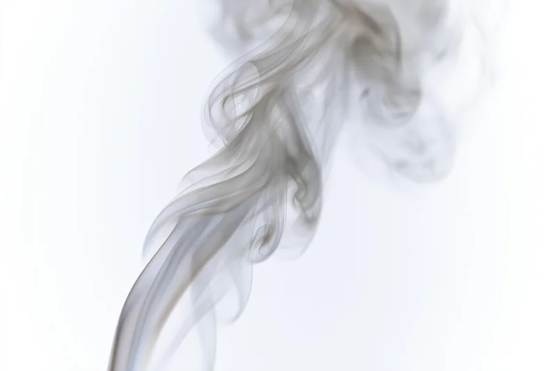 Wispy smoke plume rising and curling against a white background