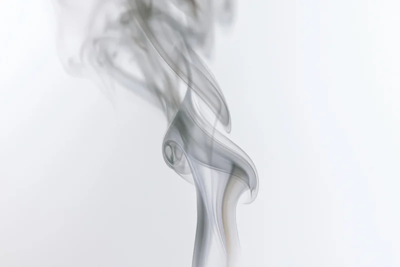 Wispy smoke plume rising and curling against a white background