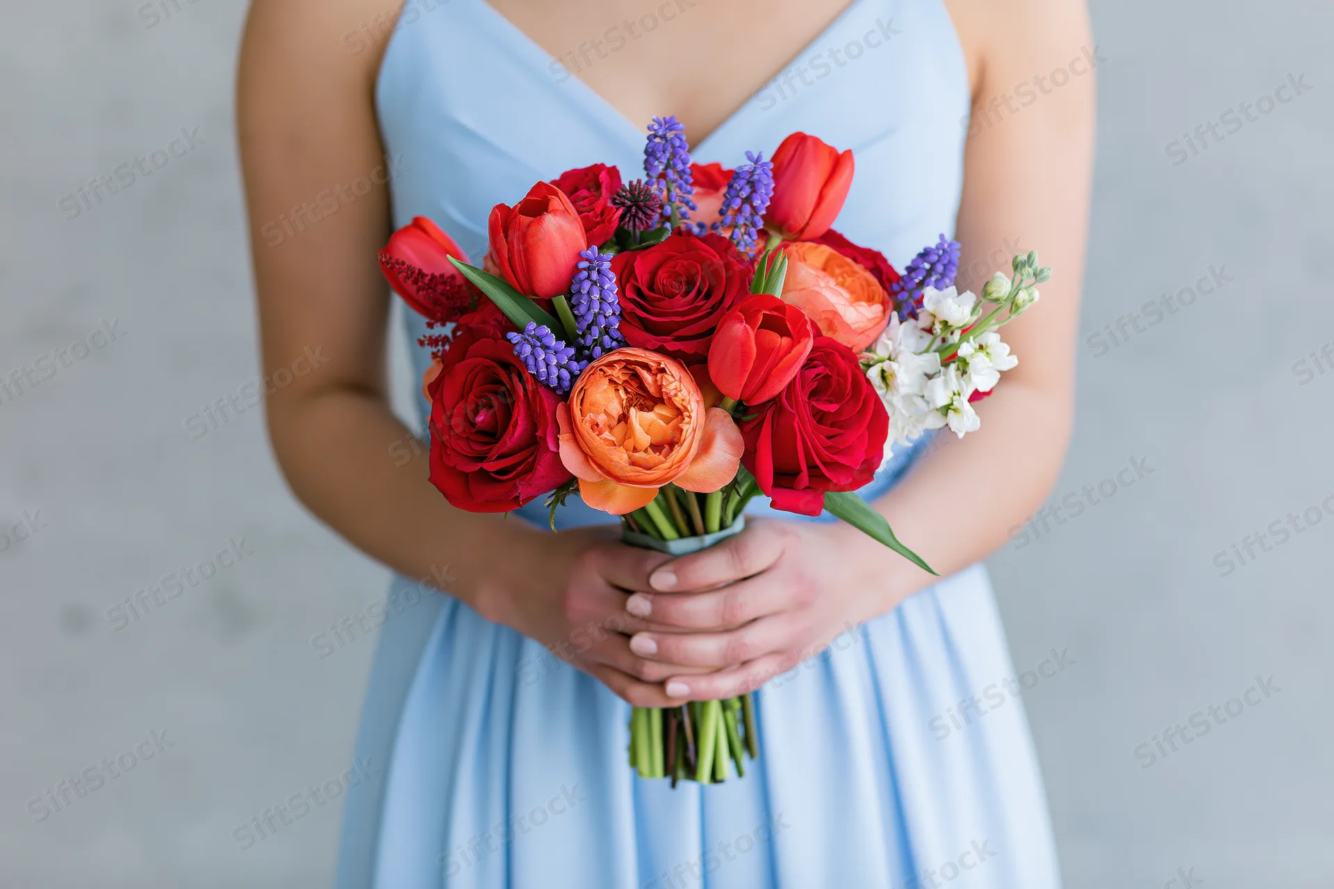 Woman holding a colorful mixed flower bouquet in a light blue dress