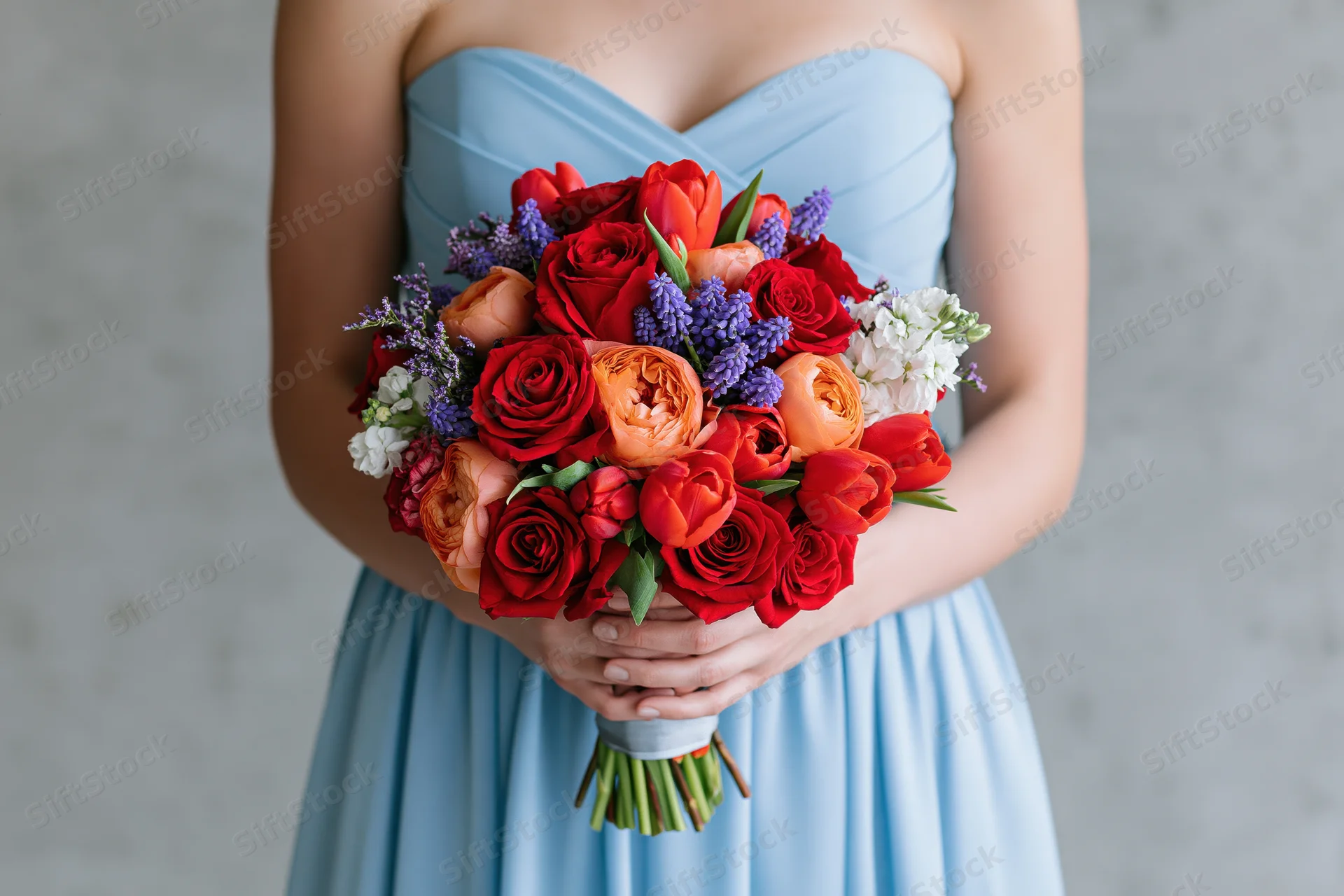 Woman holding a colorful floral bouquet in a light blue strapless dress