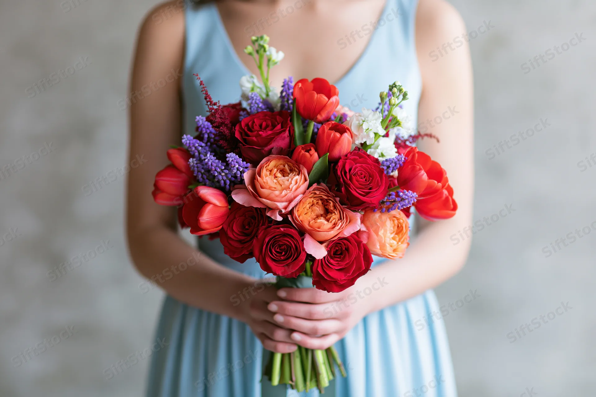 Woman holding a colorful mixed flower bouquet in a light blue dress
