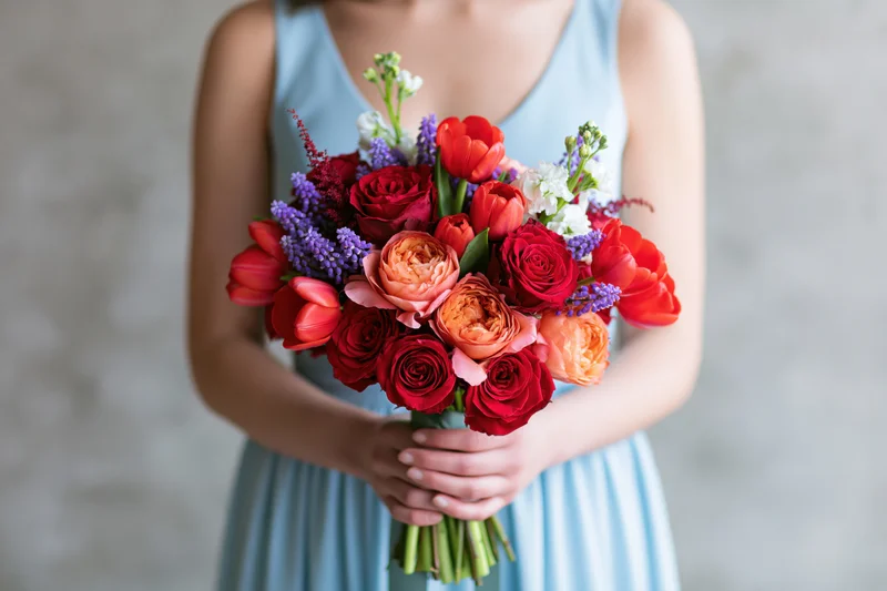 Woman holding a colorful mixed flower bouquet in a light blue dress