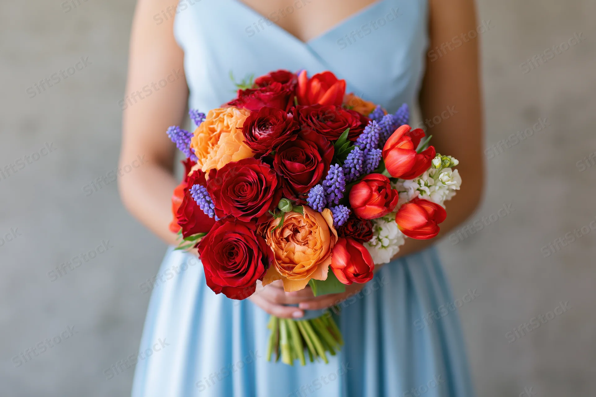 Woman holding a colorful mixed flower bouquet in a light blue dress