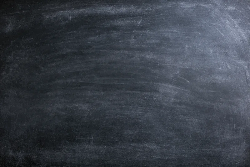 Worn chalkboard surface filling the frame with smudged residue and erased marks