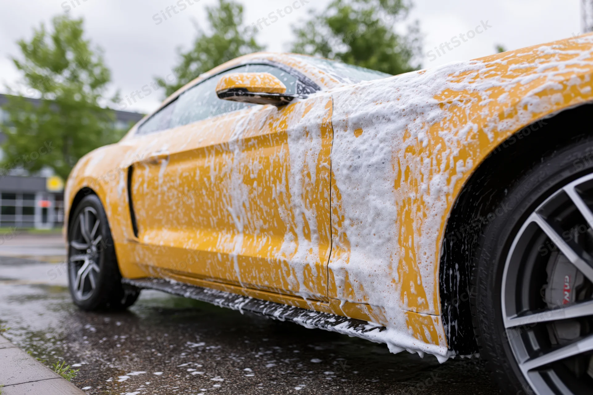 Yellow ford mustang coupe covered in thick white soap foam during outdoor car wash