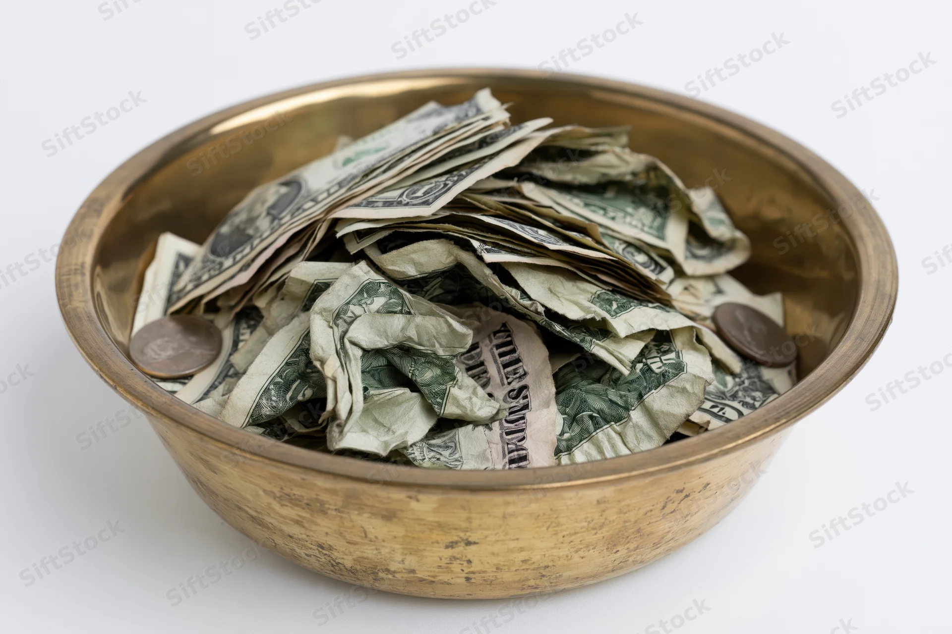 Brass offering bowl filled with crumpled us dollar bills and coins on white background
