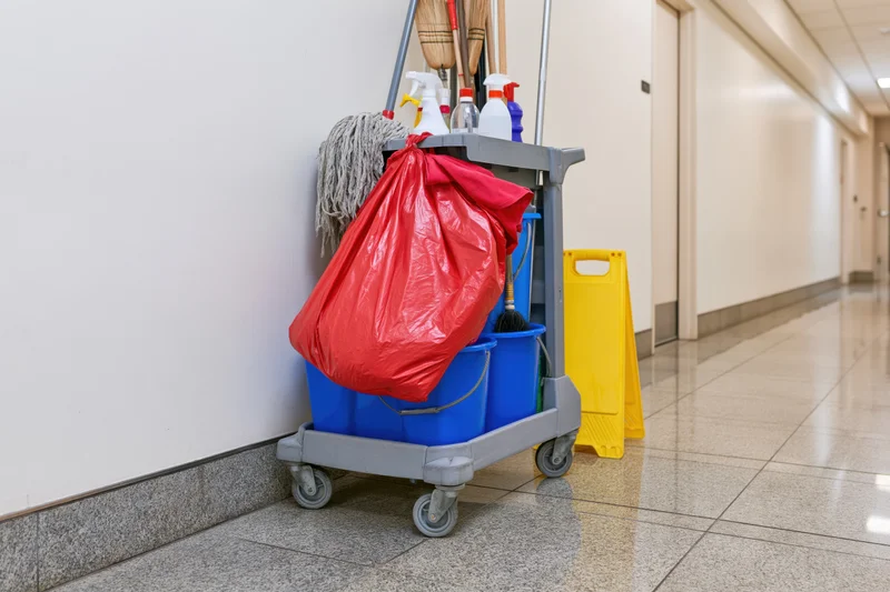 Janitorial cleaning cart loaded with mops and supplies in a hallway