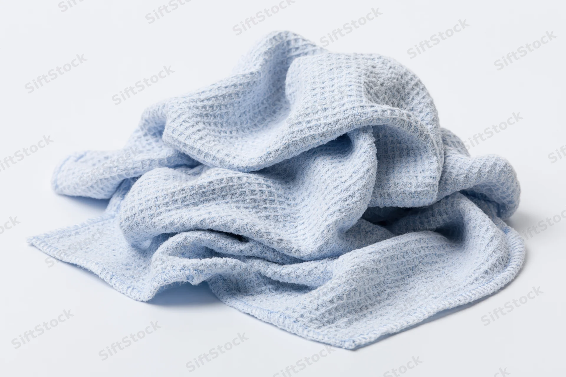 Crumpled light blue microfiber cloth with waffle texture on white background