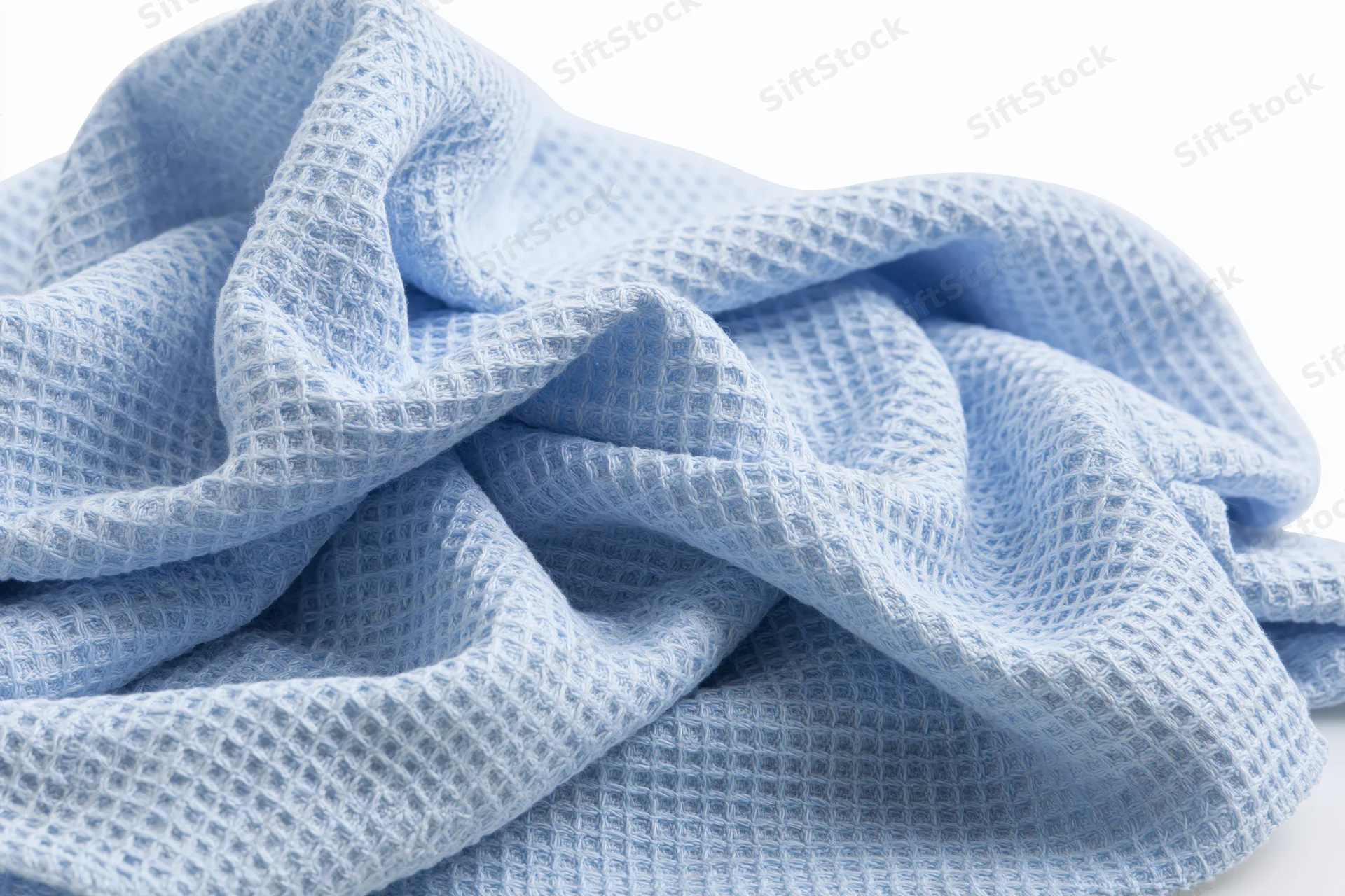 Crumpled light blue microfiber cloth with waffle texture on white background