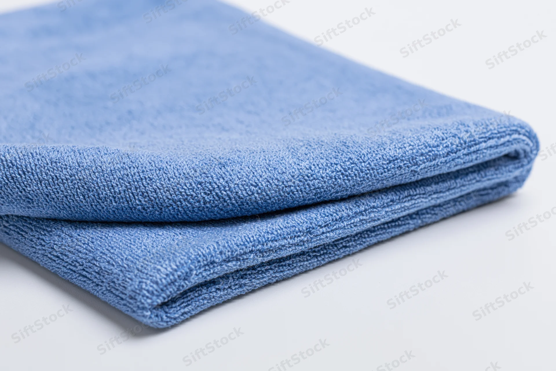 Folded blue microfiber cleaning cloth on white background
