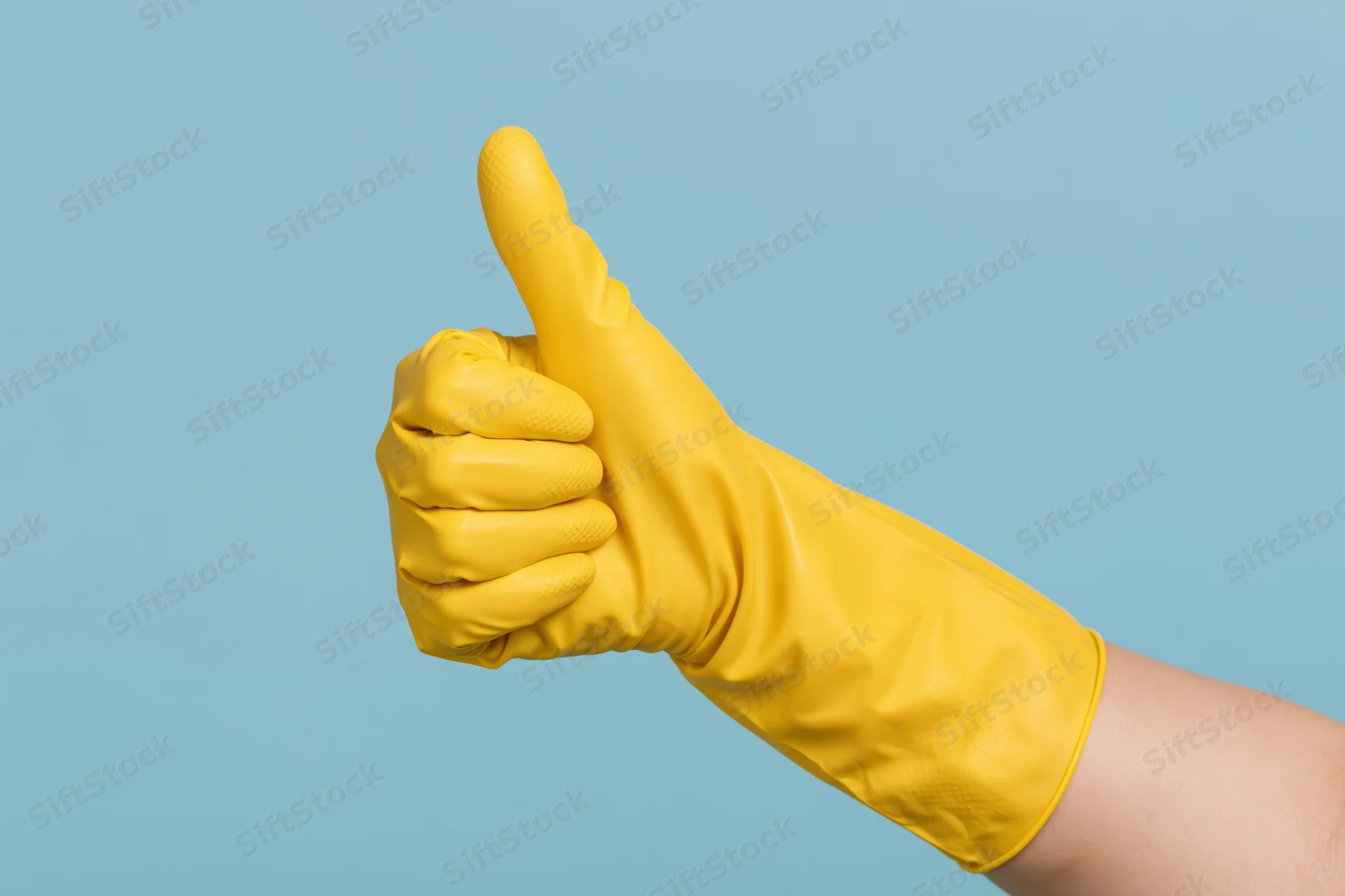 Hand in yellow rubber cleaning glove giving thumbs up against blue background