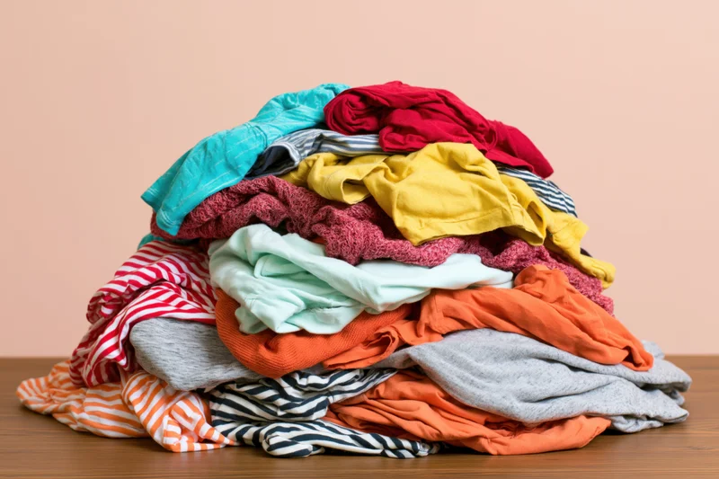 A large messy pile of mixed clothing heaped on a wooden surface
