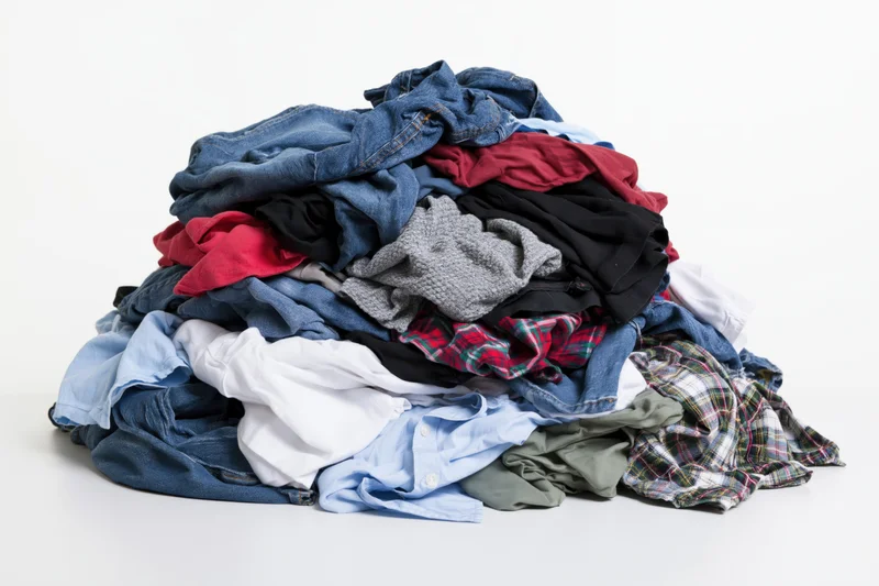 Messy pile of mixed clothing heaped together on white background