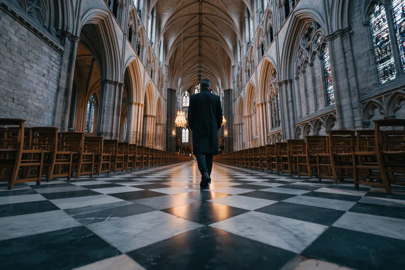 Man walking down the central aisle of a gothic cathedral interior