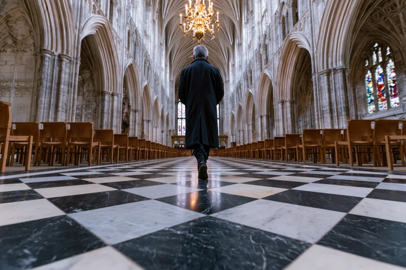 Man walking down central aisle of gothic cathedral interior