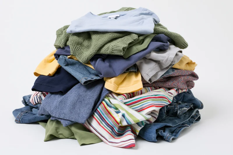 Messy pile of mixed casual clothing heaped on plain white background