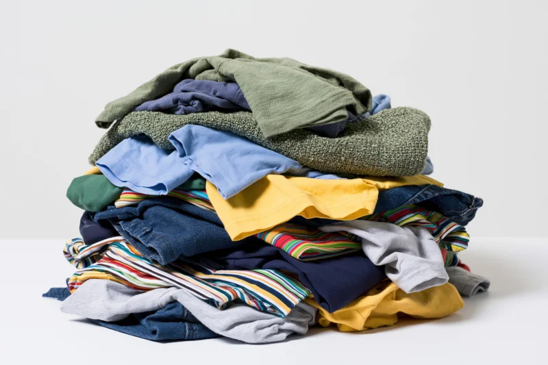 Messy pile of mixed casual clothing heaped on plain white surface