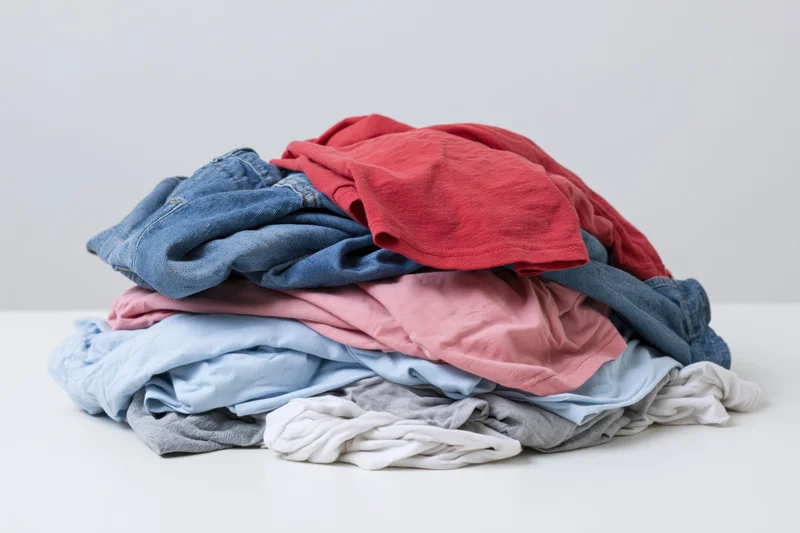 Pile of wrinkled laundry clothes heaped on white surface