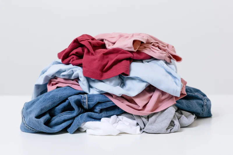 Messy pile of wrinkled clothes heaped on a white surface