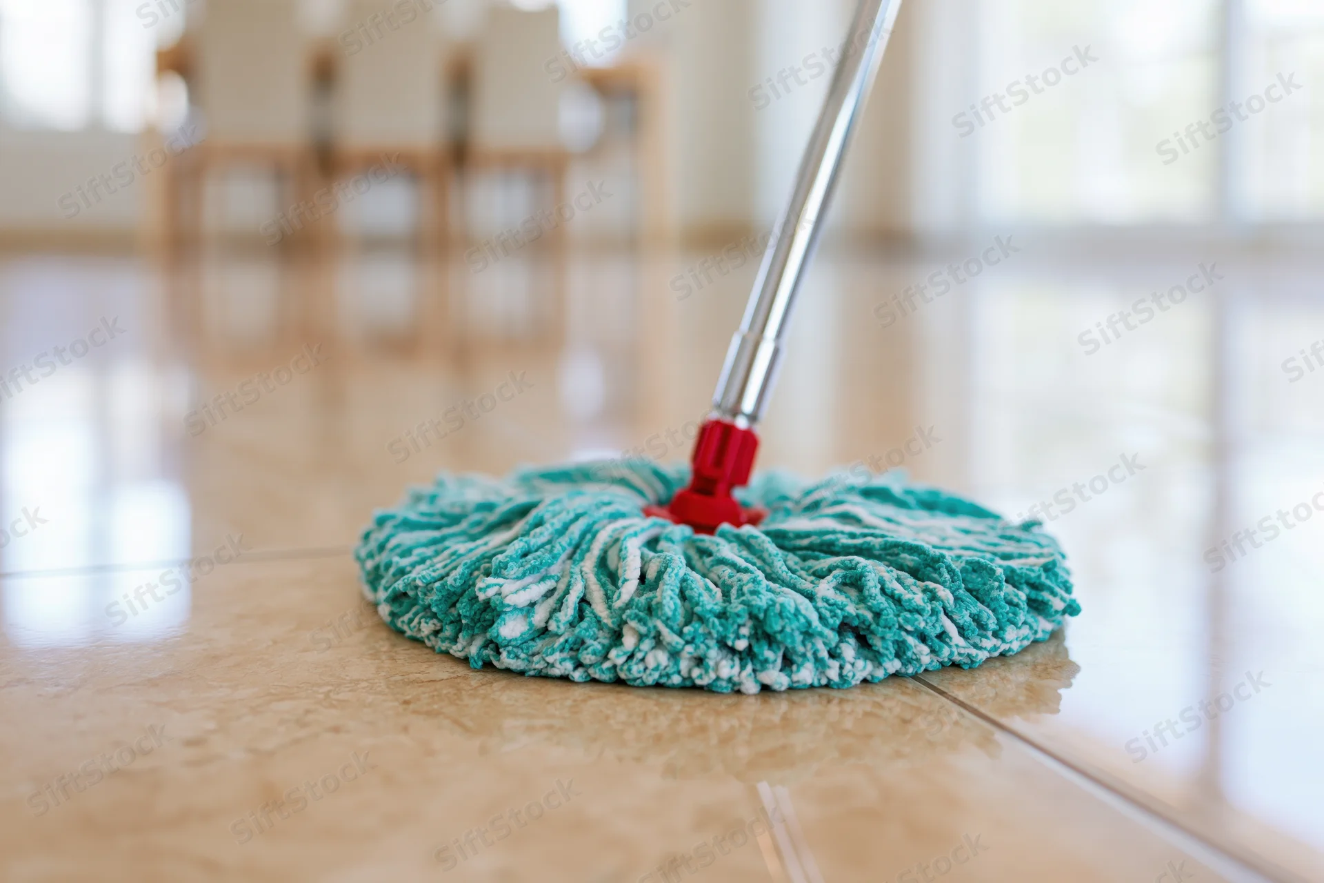 Microfiber mop head resting on polished tile floor in home interior