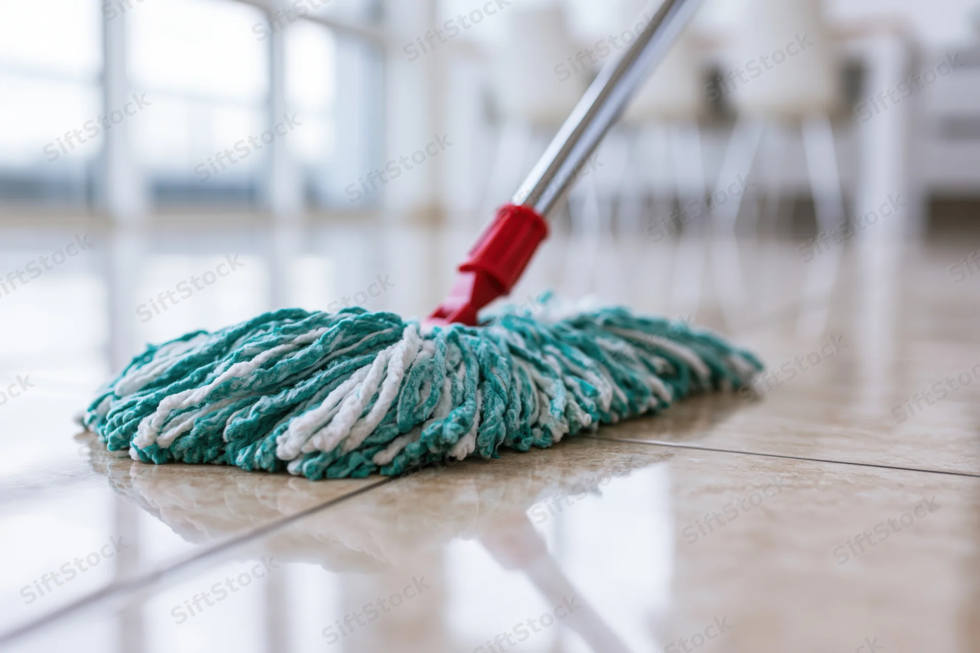 Microfiber mop head resting on polished tile floor with chrome handle