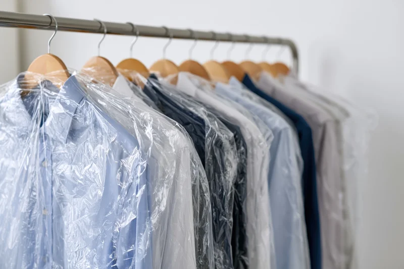 Row of freshly dry-cleaned shirts on wooden hangers in a closet