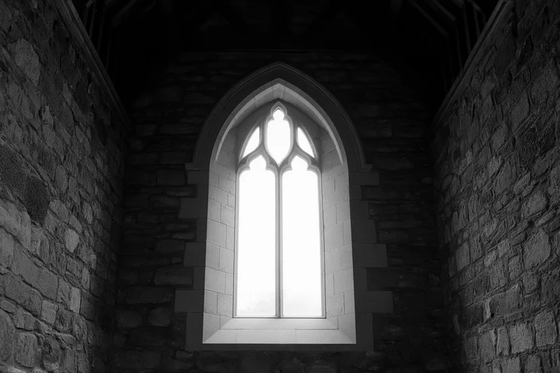 Gothic arched window glowing with light in stone church interior
