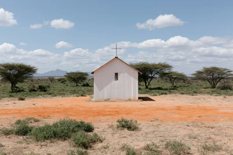 Small white corrugated metal church with cross on roof in dry savanna landscape