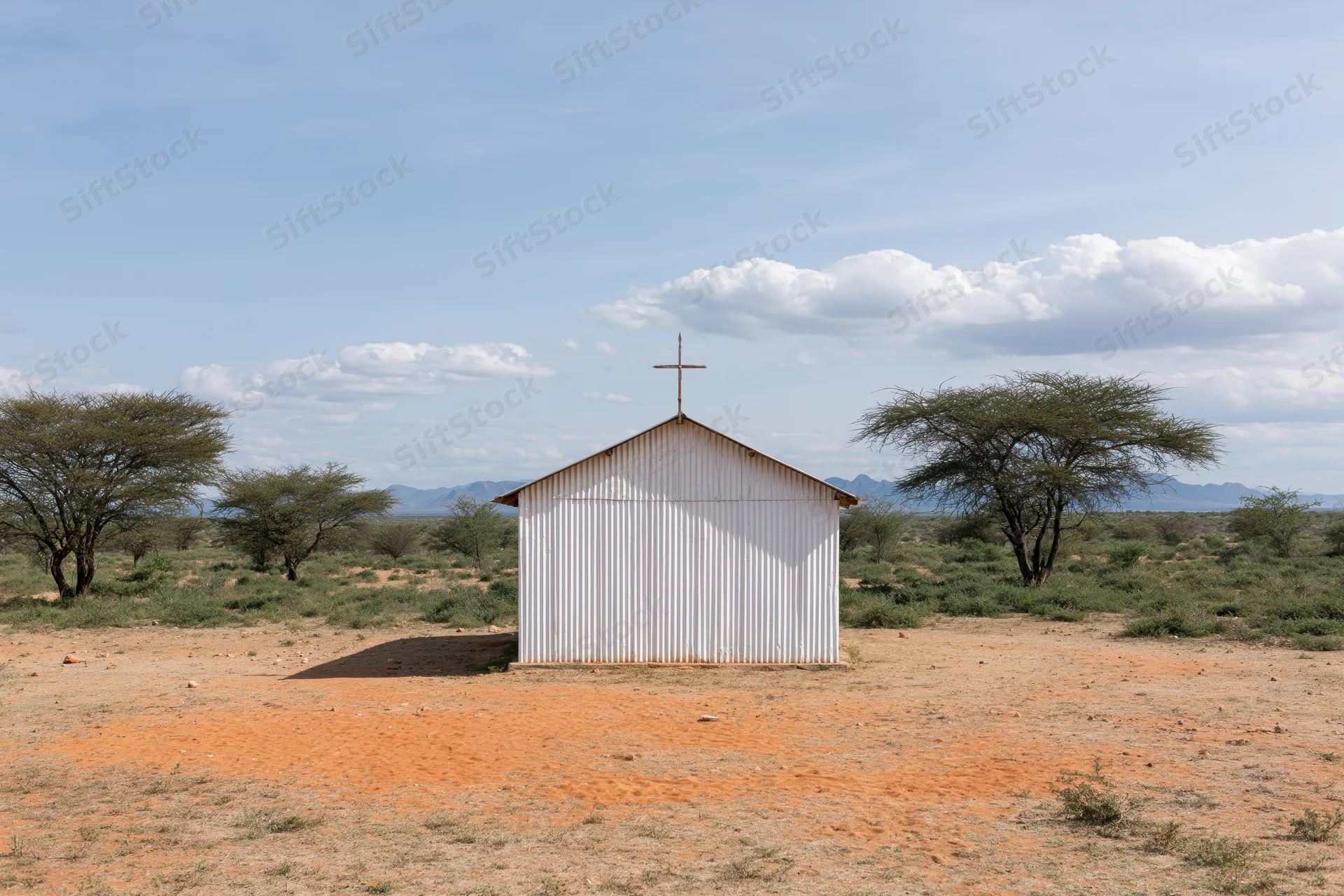 Small white corrugated metal church with cross on roof in dry savanna landscape