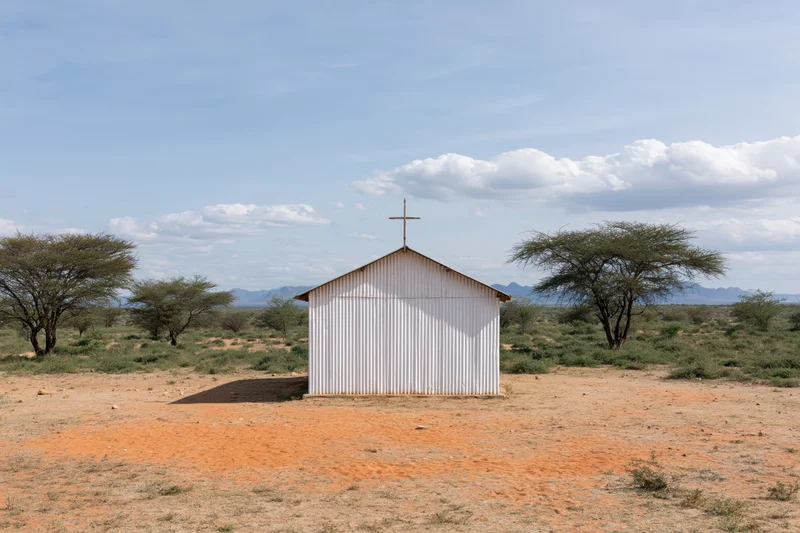 Small white corrugated metal church with cross on roof in dry savanna landscape
