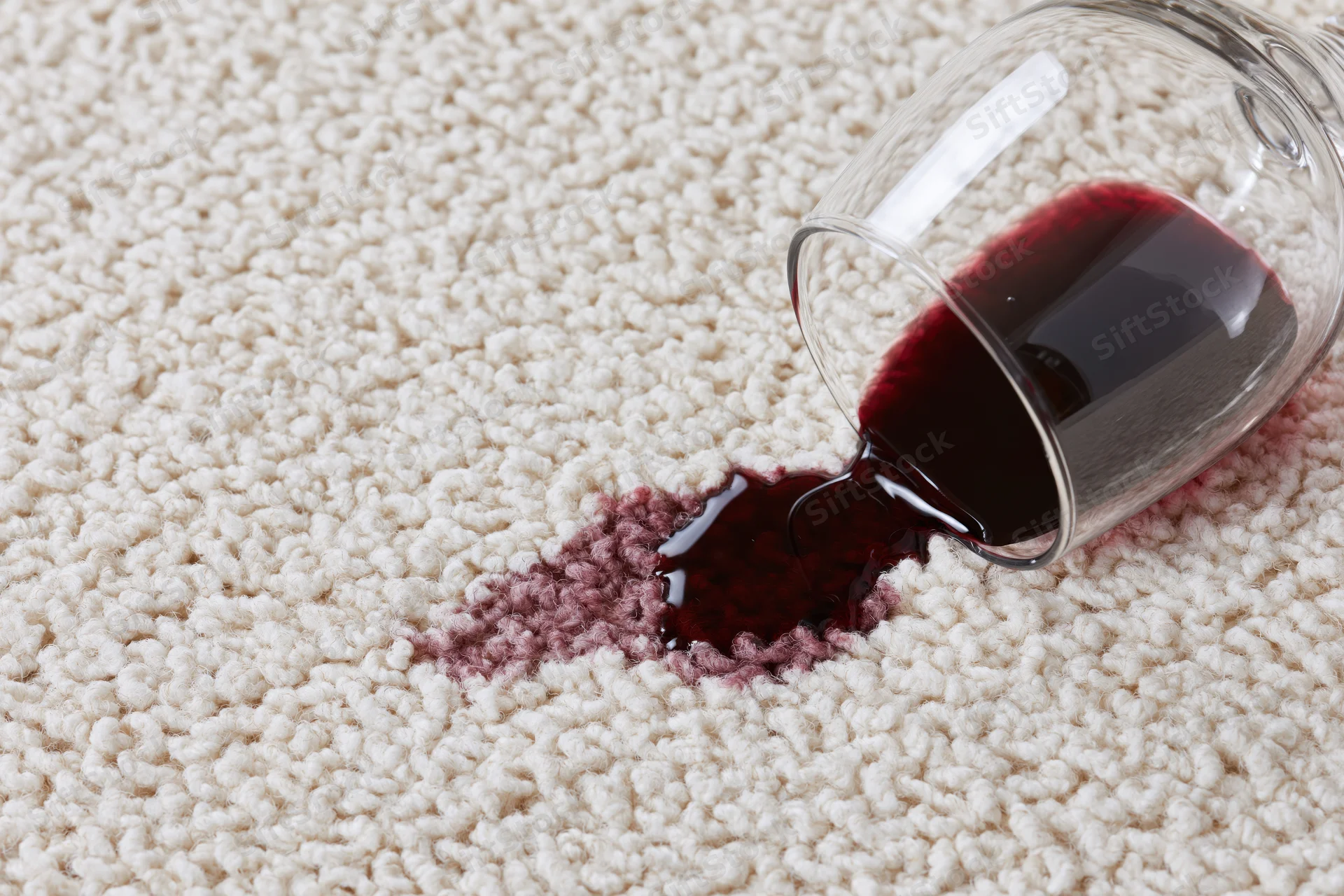 Tipped-over wine glass lying on its side on cream carpet