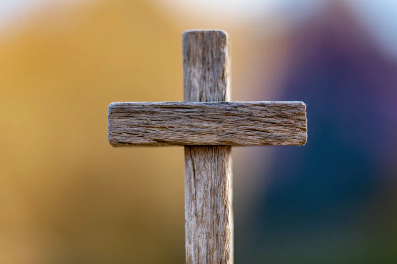 Weathered wooden cross standing upright in a cemetery at dusk