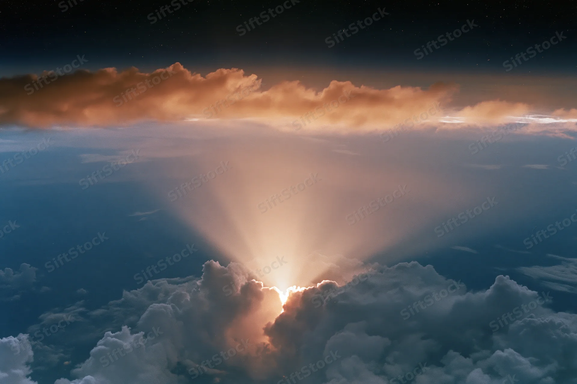Aerial view through layered clouds toward sunlit horizon at twilight