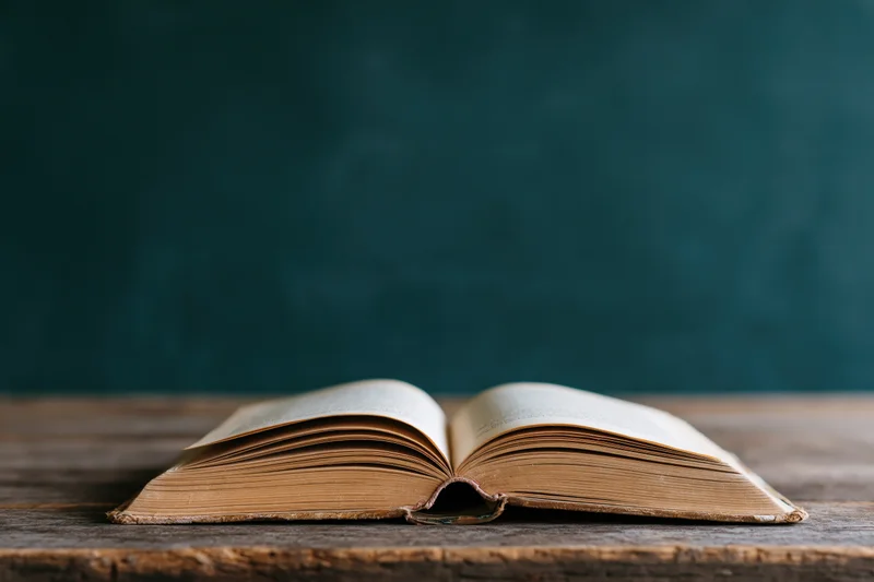 Open vintage hardcover book resting on a worn wooden desk
