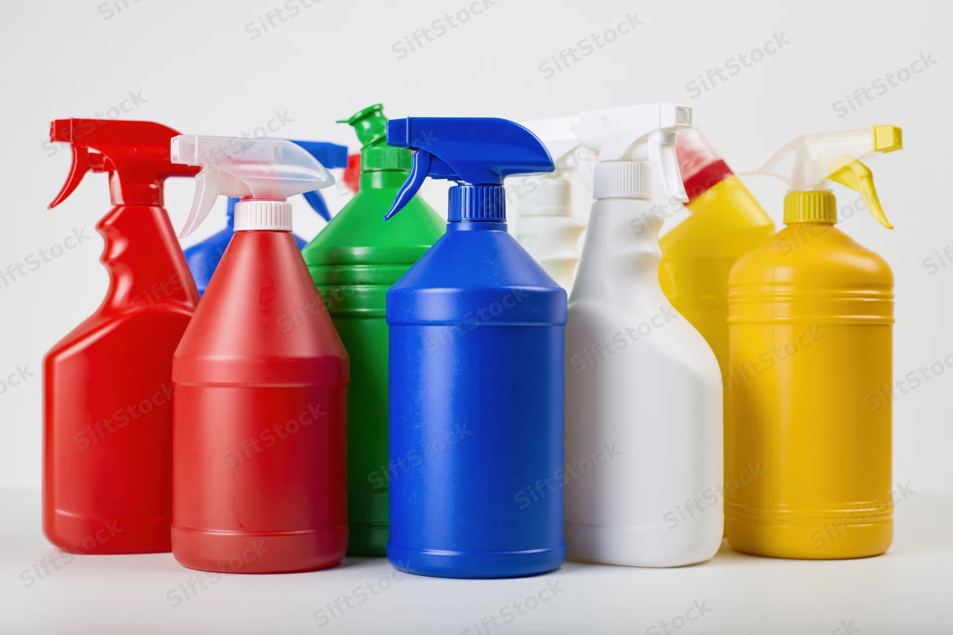 Colorful cleaning spray bottles arranged in a row on a white surface