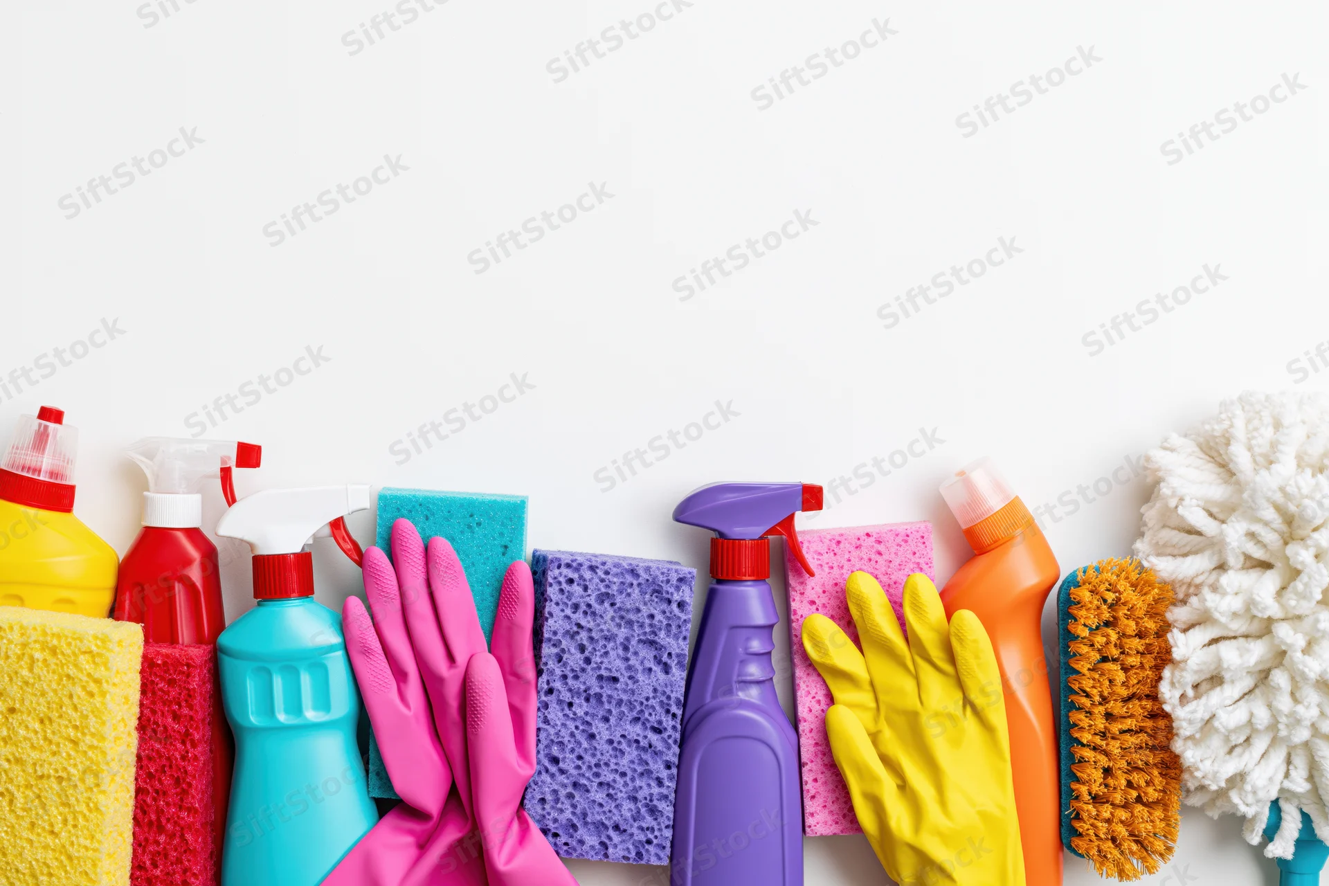 Colorful household cleaning supplies arranged in a row on white background with copyspace