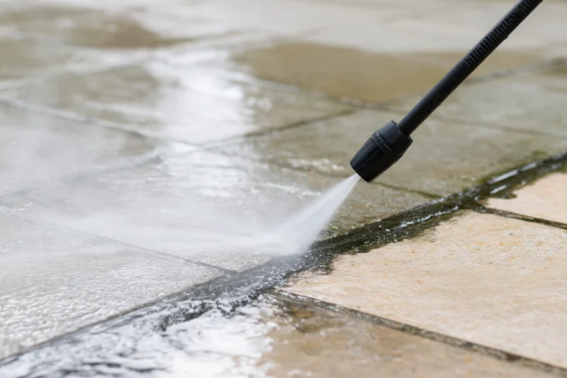 Pressure washer wand spraying water onto a tiled patio surface
