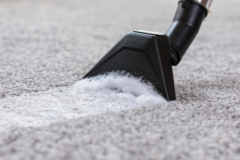 Black triangular vacuum nozzle extracting white foam from carpet