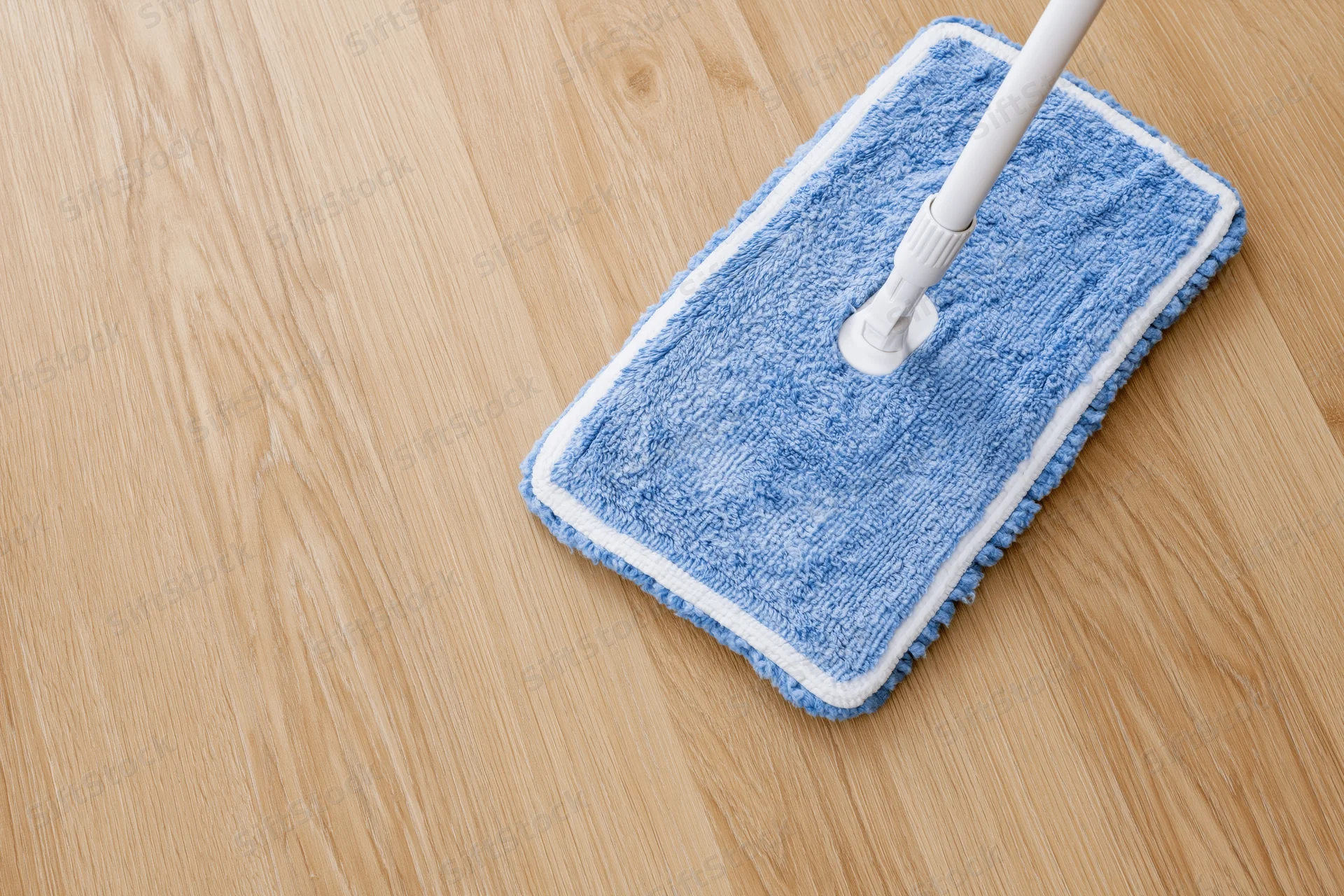 Blue microfiber mop head on wooden floor with white handle