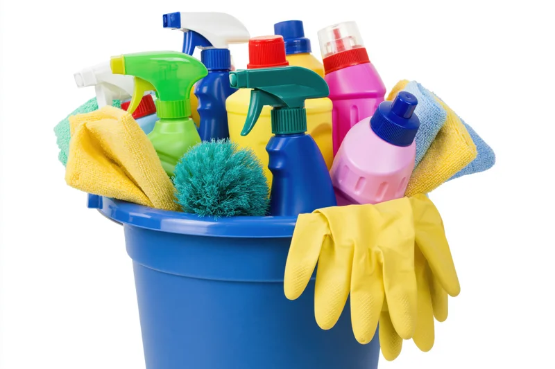 Blue plastic bucket filled with colorful cleaning supplies and gloves on white background