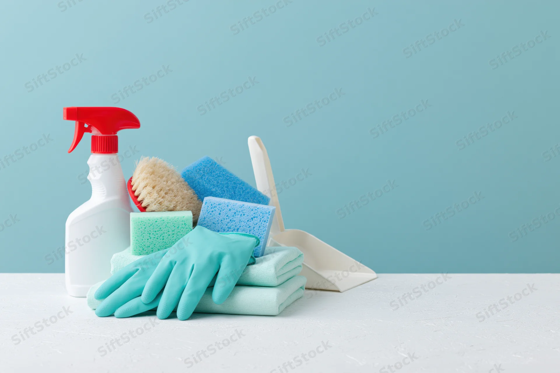 Cleaning supplies arranged on a white surface against a solid blue background