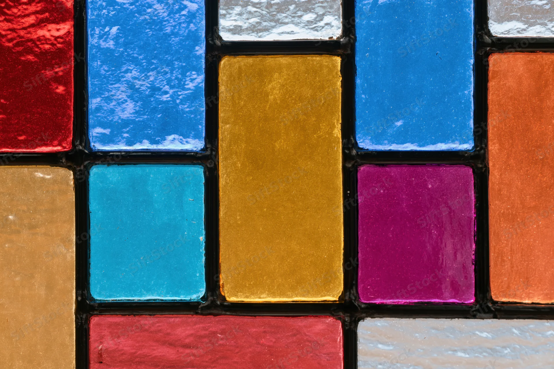 Close-up of a geometric stained glass window panel with colorful glass pieces arranged in a grid pattern