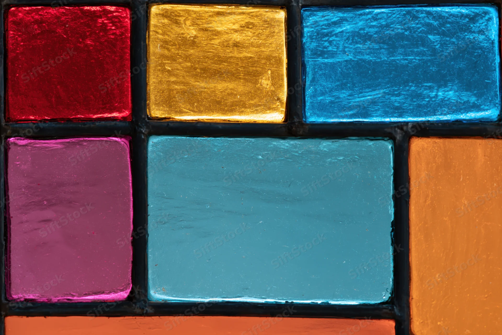 Close-up of a geometric stained glass window panel with colorful translucent glass squares arranged in a grid pattern