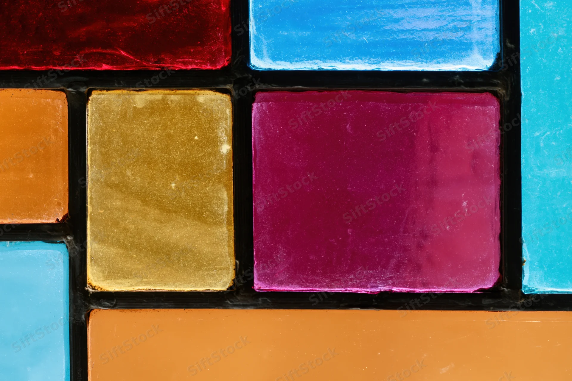 Close-up of a geometric stained glass window panel with vibrant colored glass pieces arranged in a grid pattern