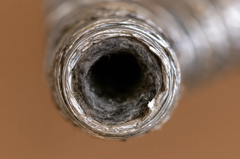 Close-up view looking directly into the corroded interior of a metal pipe